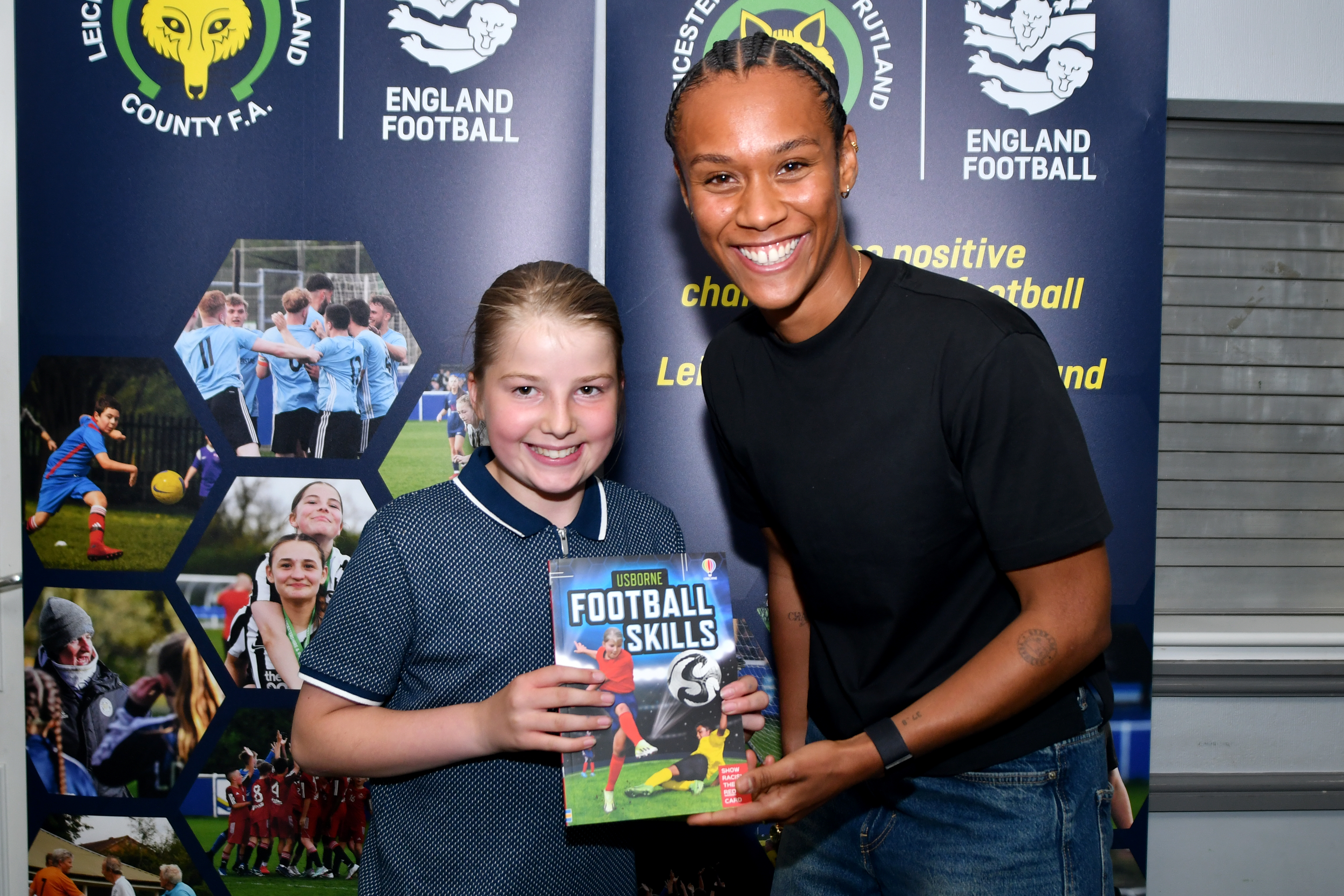 Adult standing next to a child holding up a book titled Football Skills.