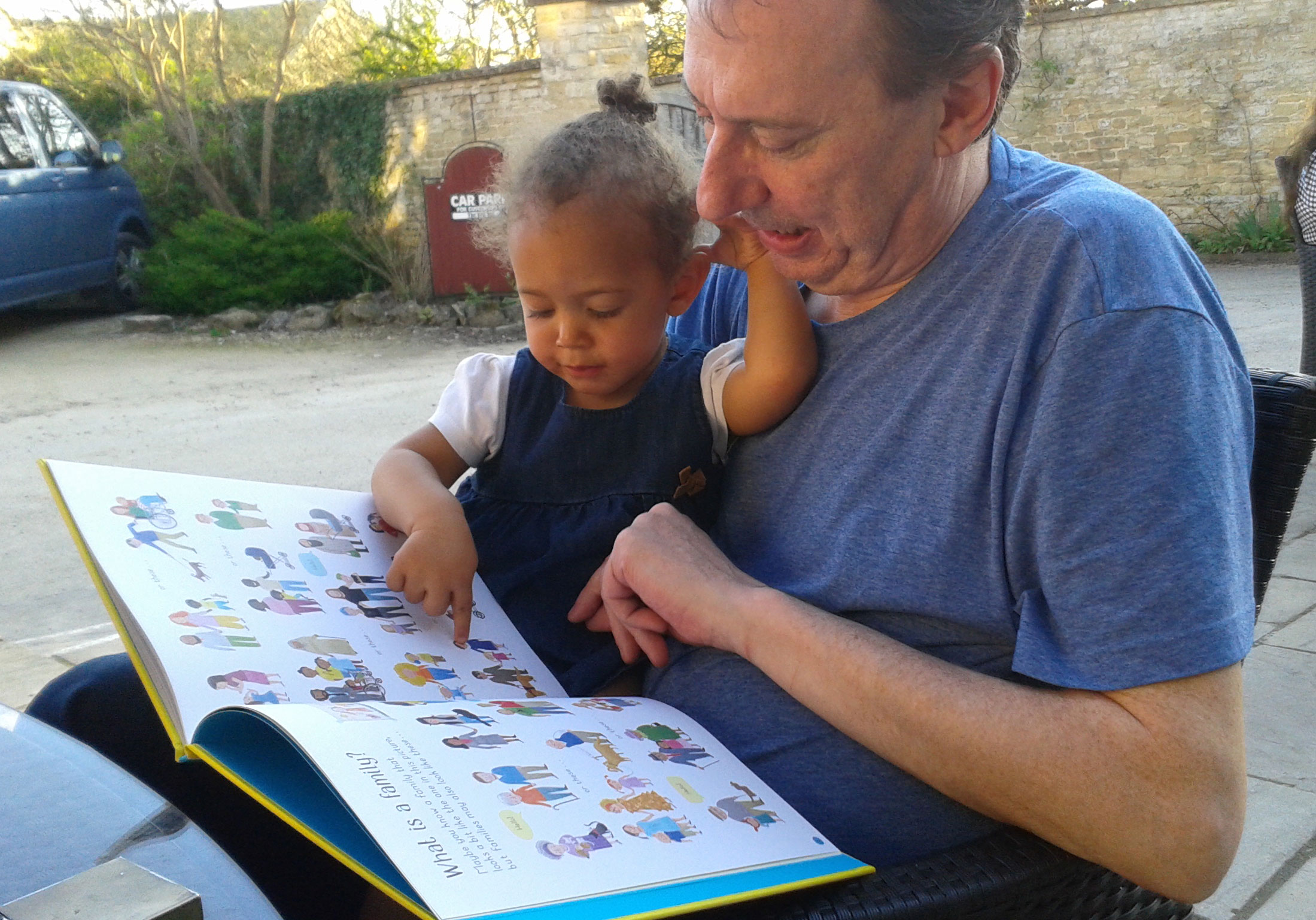 Great-uncle Clive reading All About Families with his great-niece Lauryn